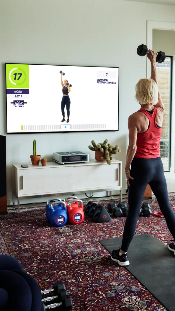 a woman lifting weights along with F45 on a Samsung TV