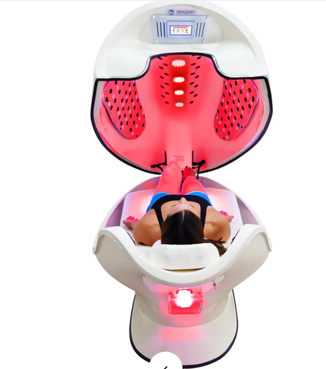 a Wellness USA red light therapy pod and a woman sitting isnde