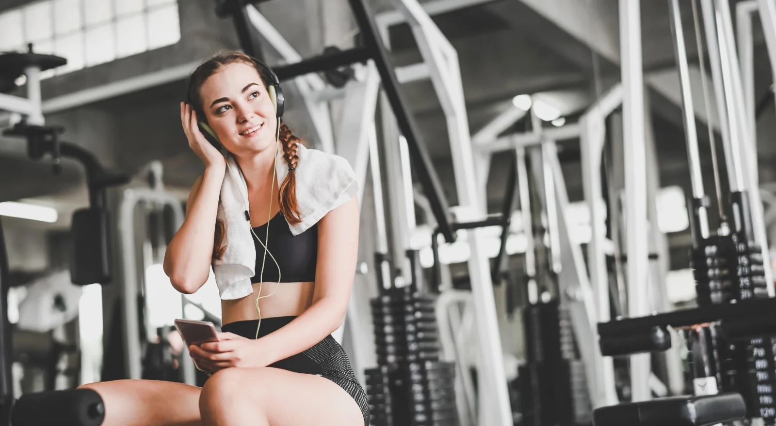 Young woman at gym with headphones on