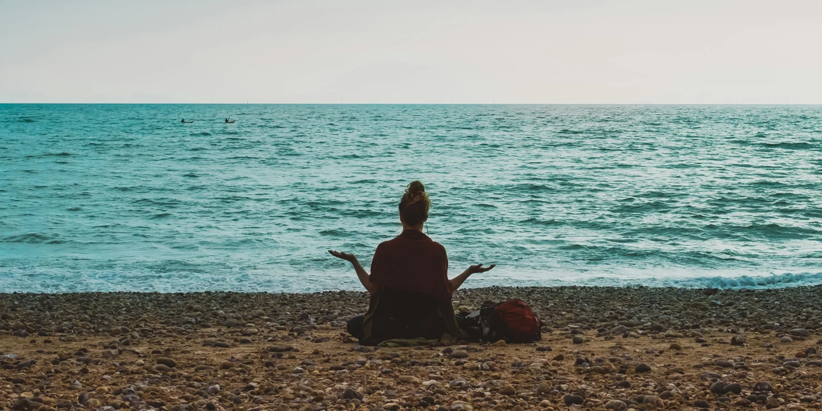 an image of a woman meditating on the beach