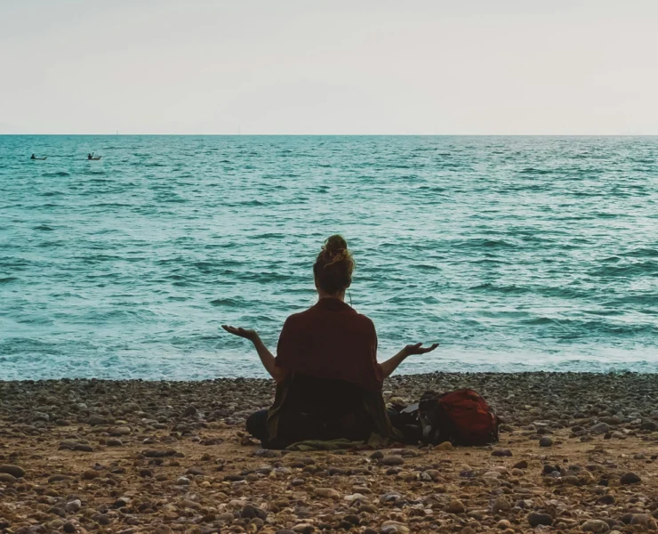 an image of a woman meditating on the beach