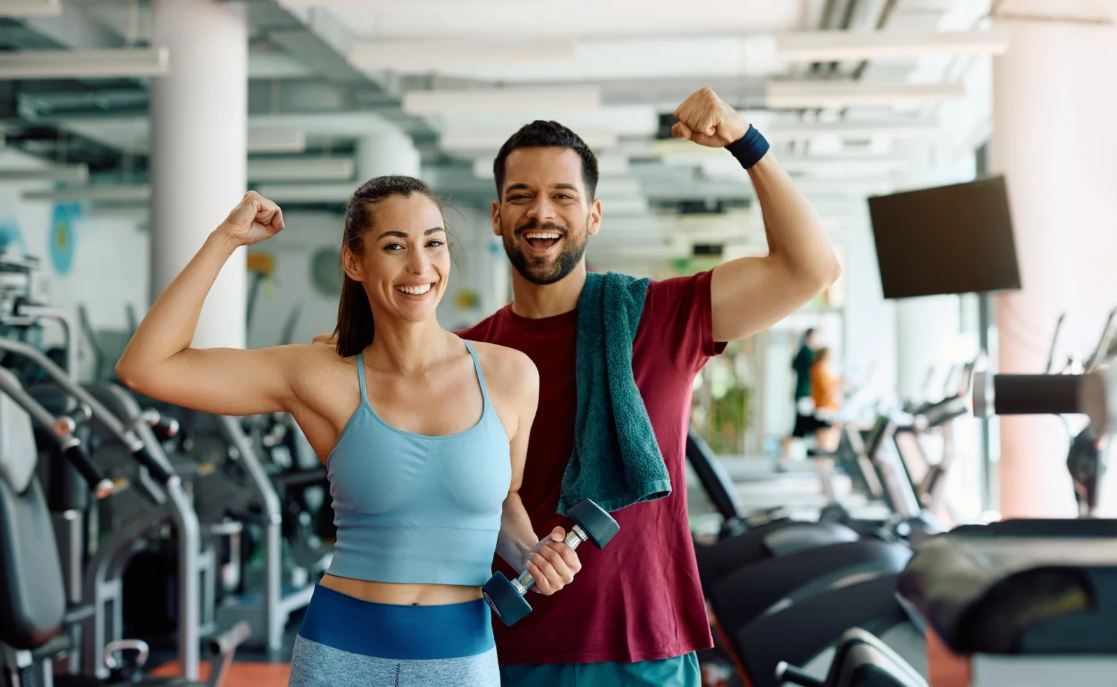 man and woman pose together inside a gym after working out