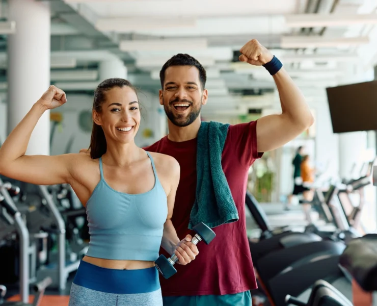 man and woman pose together inside a gym after working out