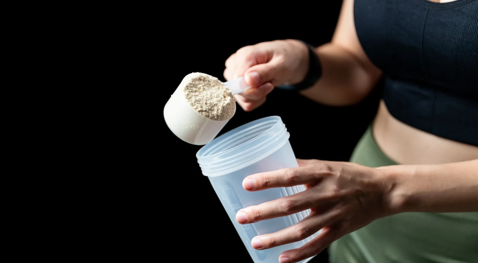 person scooping protein powder into cup