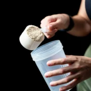 person scooping protein powder into cup