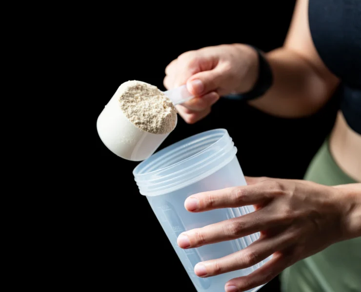 person scooping protein powder into cup