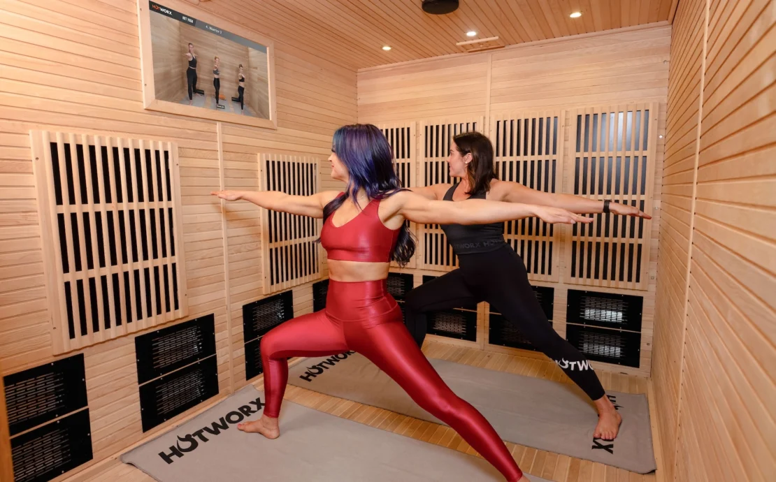 two woman do yoga in a Hotworx sauna