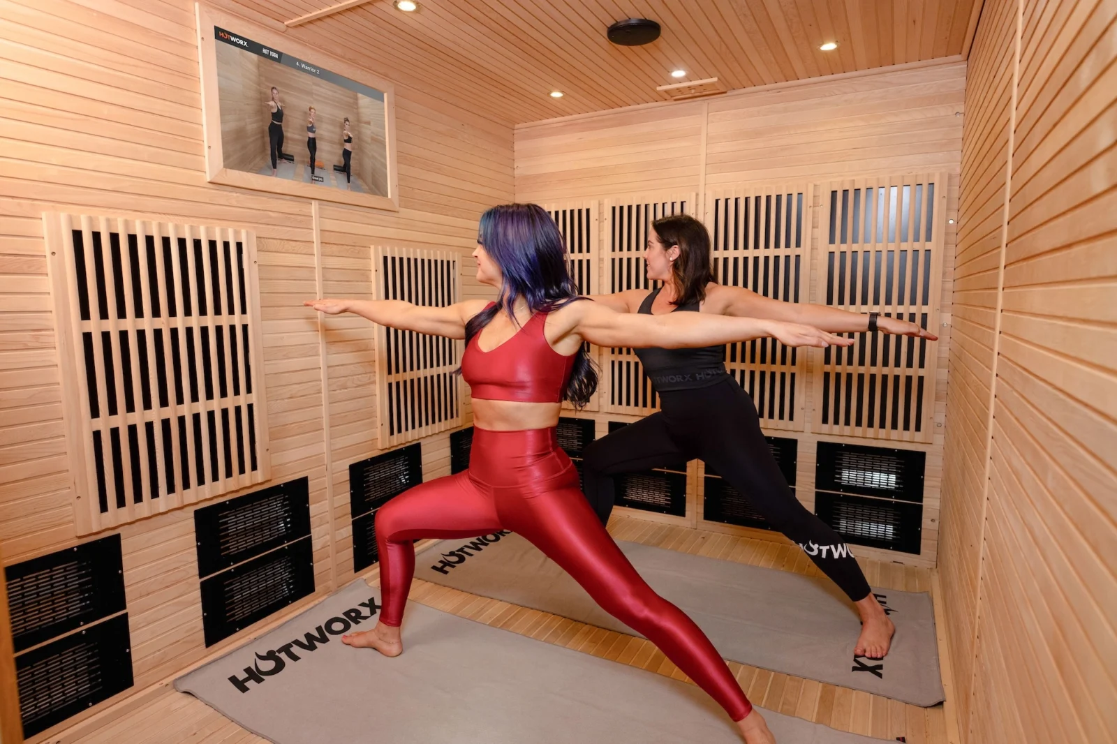 two woman do yoga in a Hotworx sauna