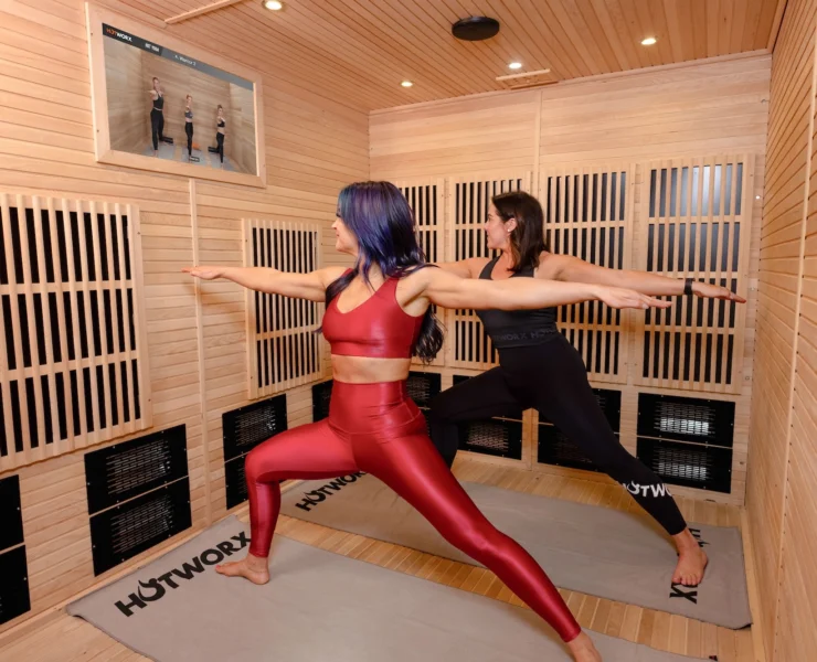 two woman do yoga in a Hotworx sauna