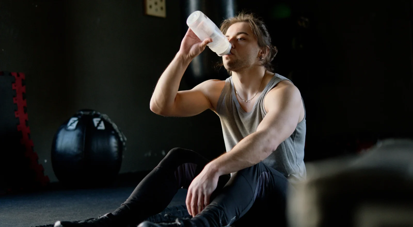 Young man drinking water in the gym