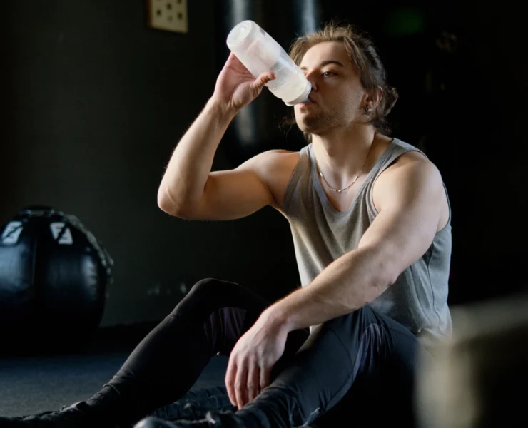 Young man drinking water in the gym