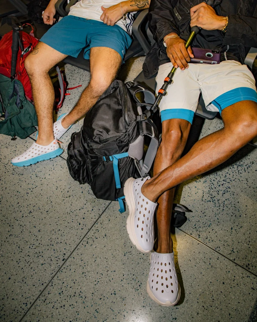 two men lounge next to a sports bag wearing Kane shoes