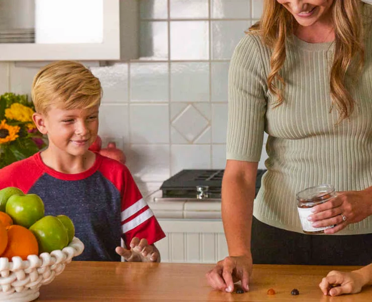 a smiling woman and young boy in the kitchen with supplements