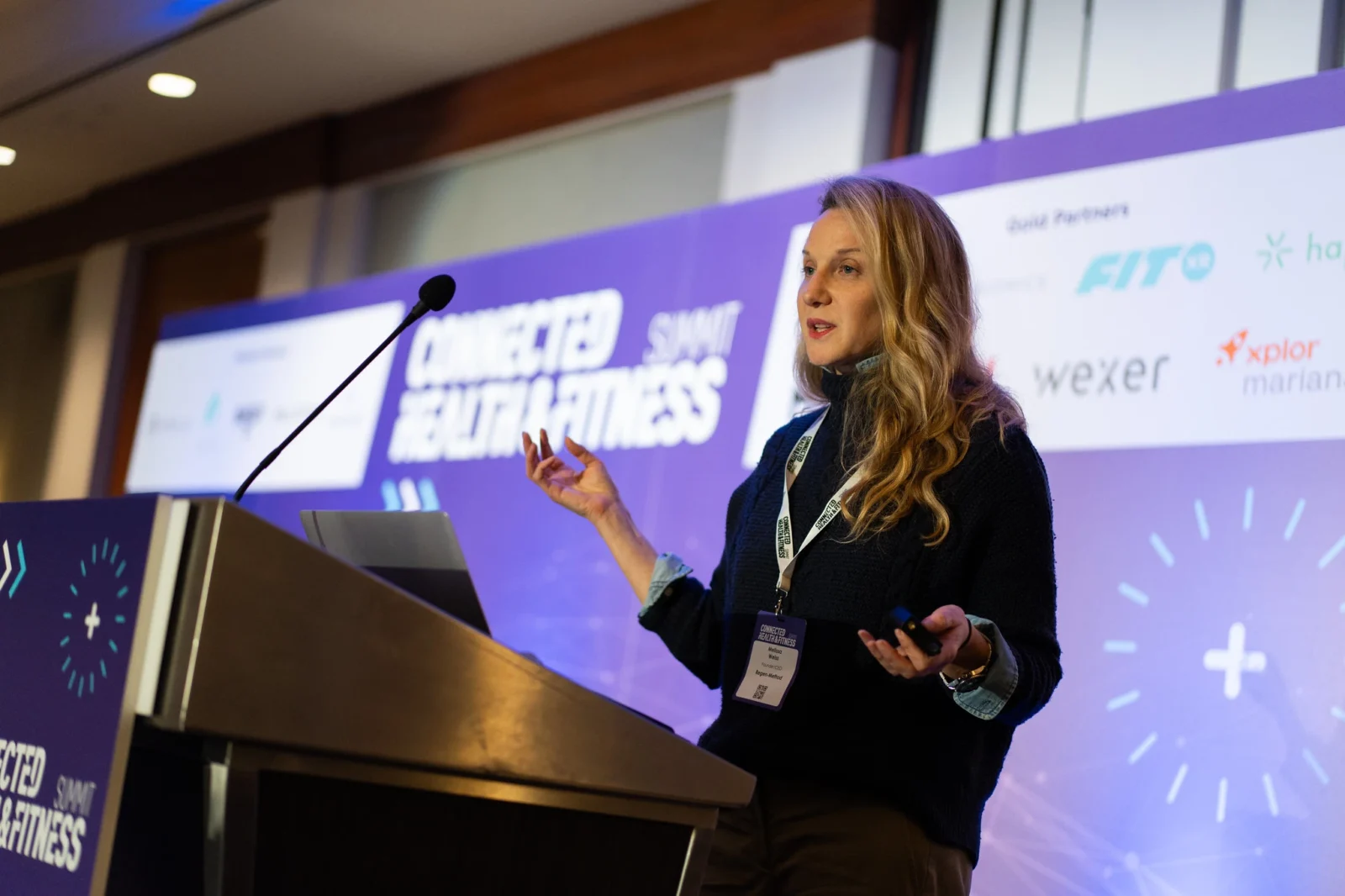 woman speaks at a podium at a fitness conference