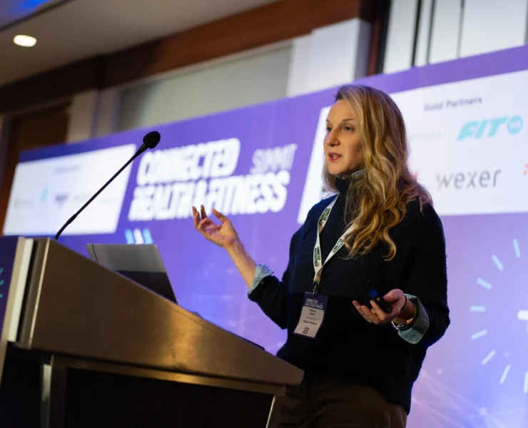 woman speaks at a podium at a fitness conference