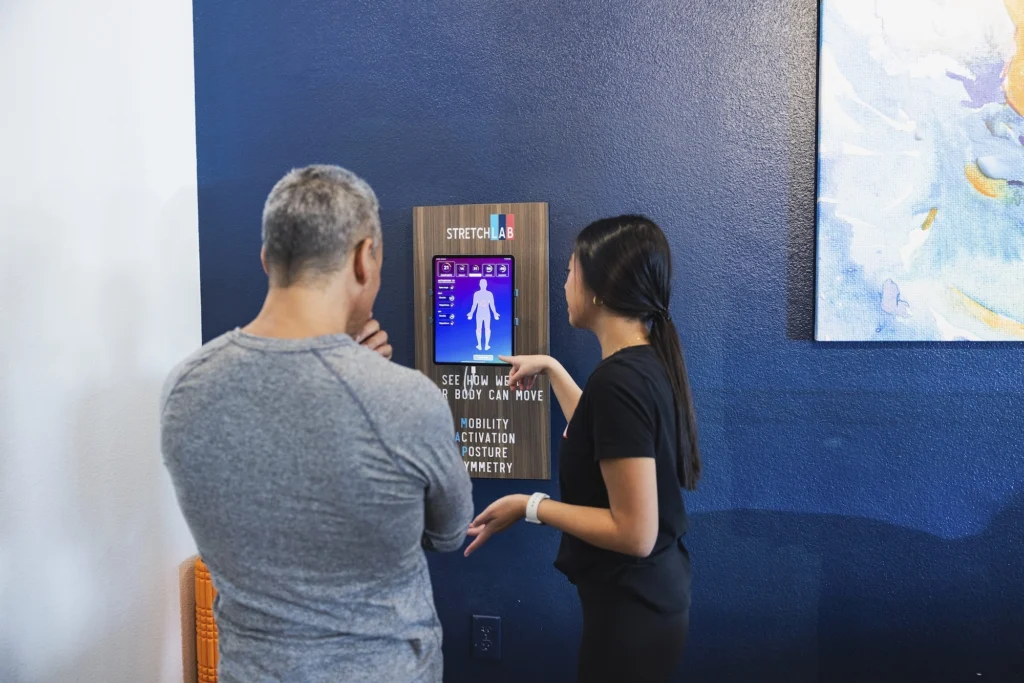 man and woman look at a screen at a StretchLab