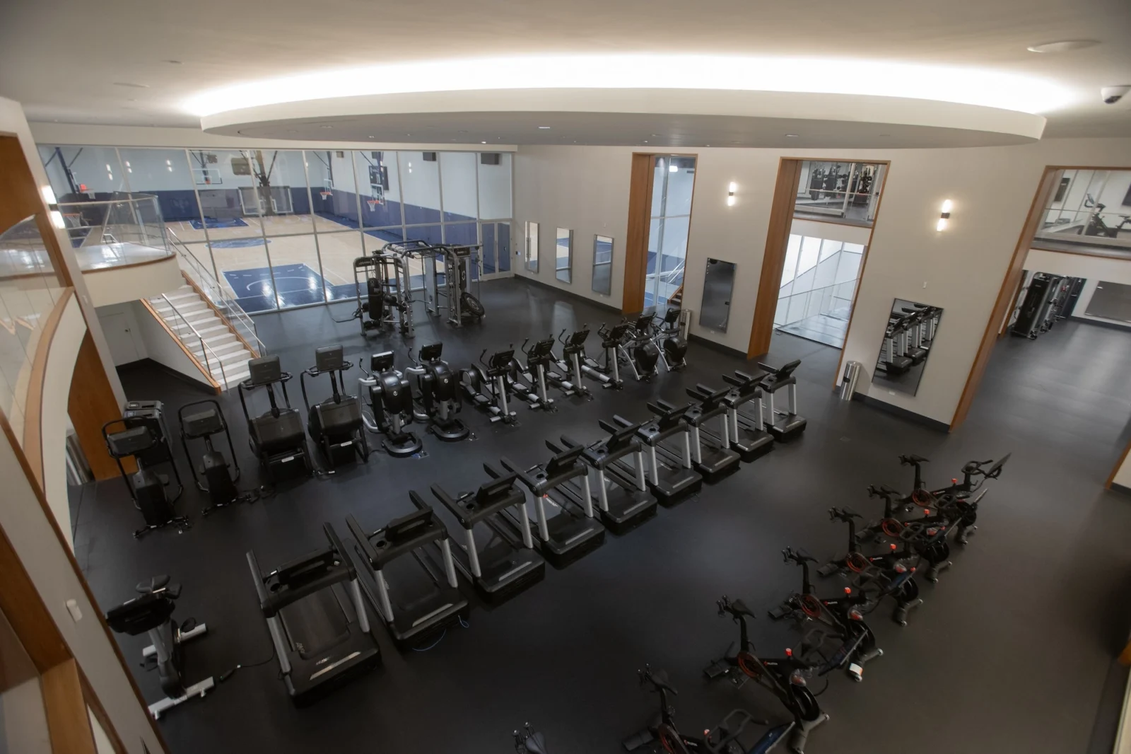 rows of fitness equipment overlook a basketball court