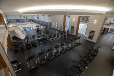 rows of fitness equipment overlook a basketball court