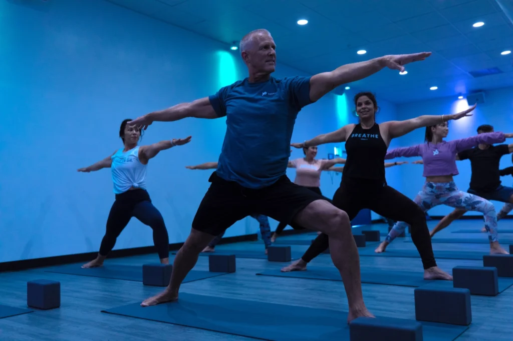 older man poses at a YogaSix class