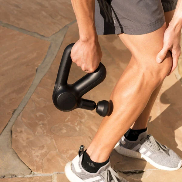 man uses Theragun on calf