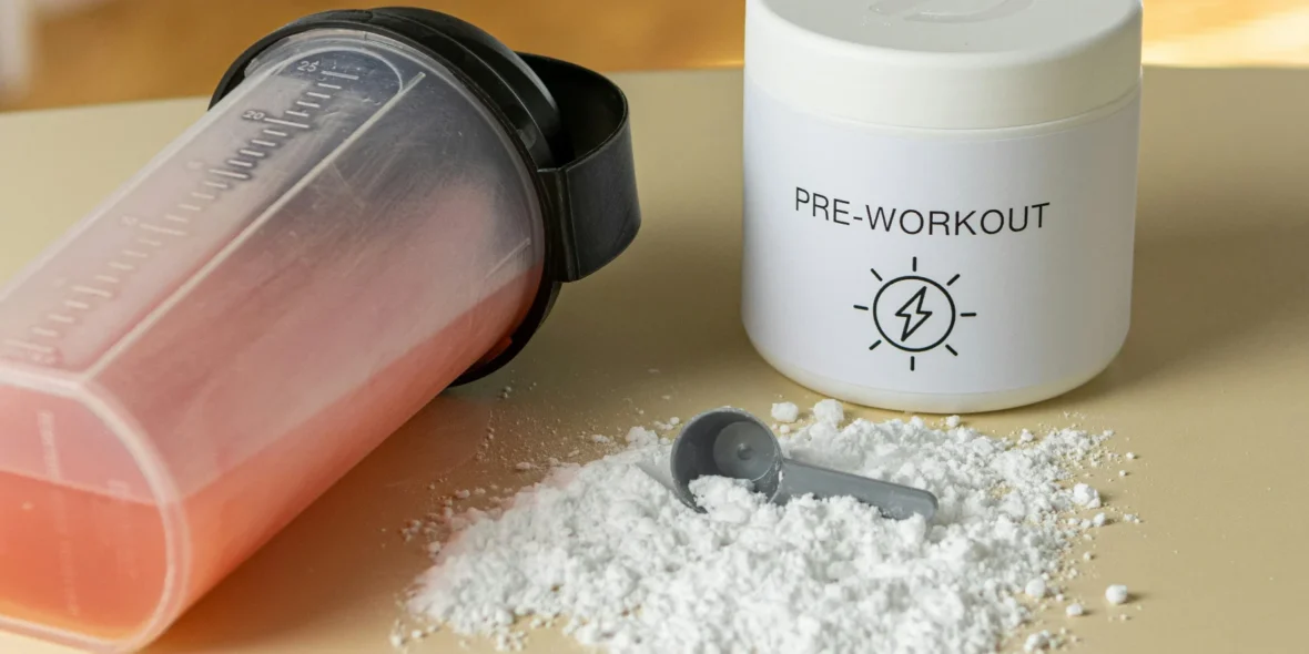 a shaker bottle next to a pre-workout supplement powder mix and a scooper