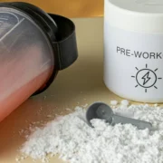 a shaker bottle next to a pre-workout supplement powder mix and a scooper