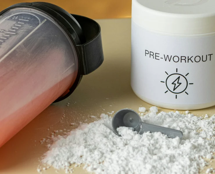 a shaker bottle next to a pre-workout supplement powder mix and a scooper