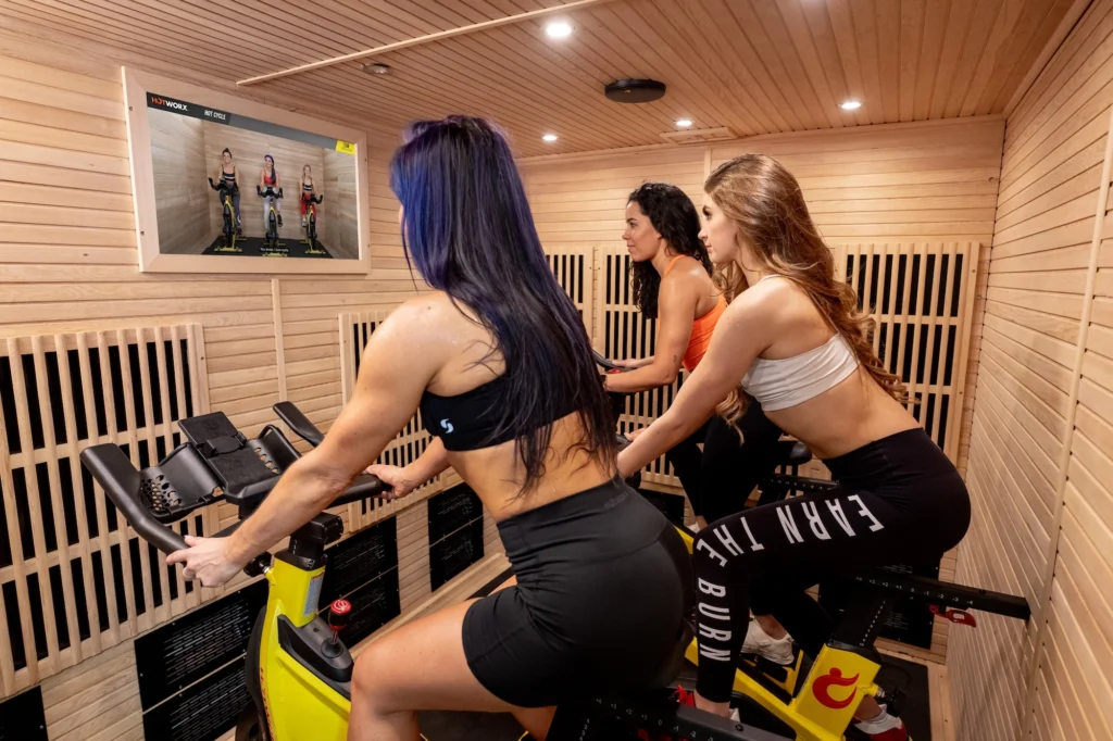 women cycle inside of a Hotworx studio