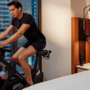 a man rides on a Peloton bike in a Hilton hotel room