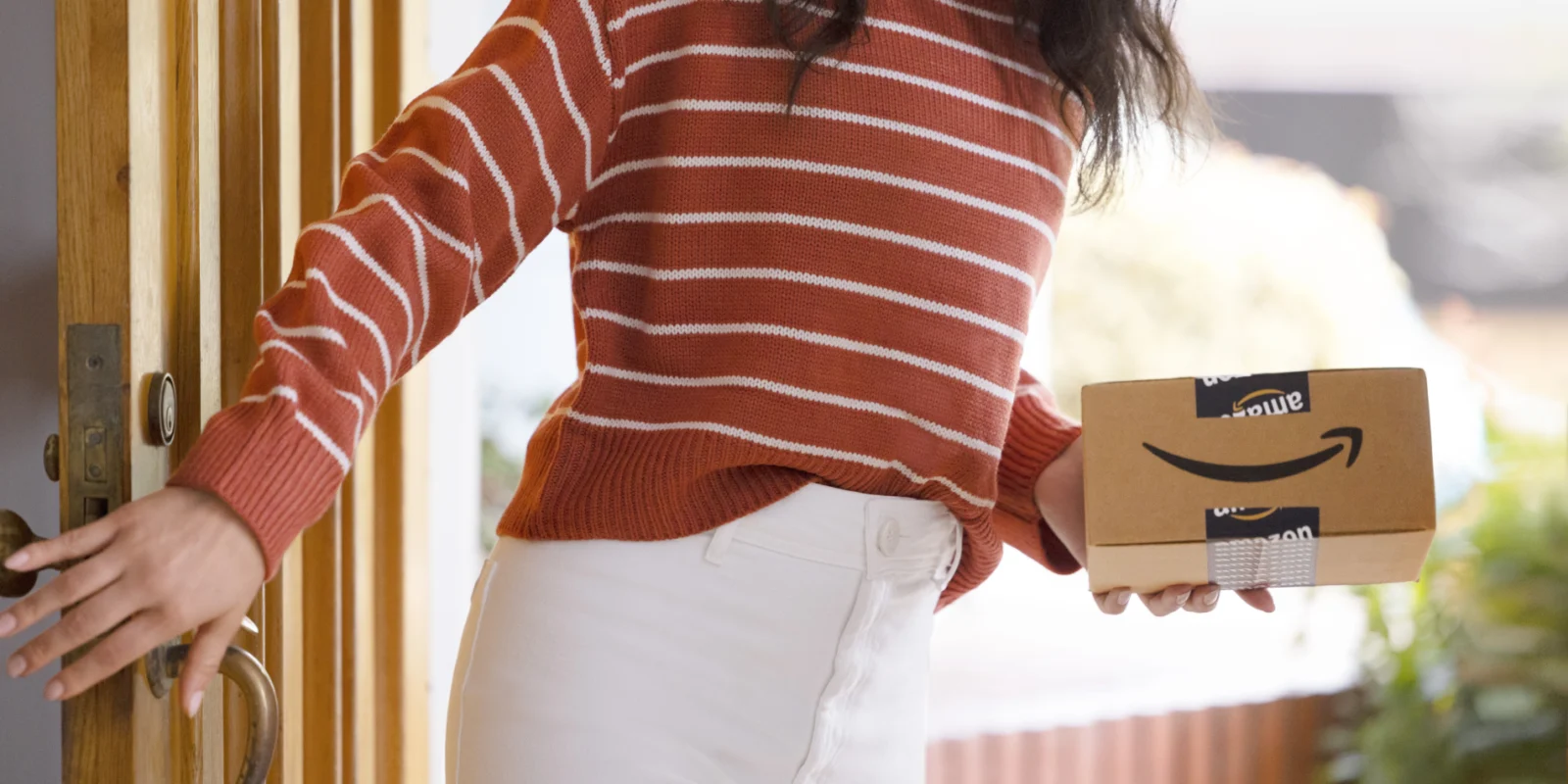 a woman holding an Amazon delivery package from the Amazon pharmacy