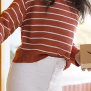 a woman holding an Amazon delivery package from the Amazon pharmacy