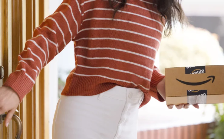 a woman holding an Amazon delivery package from the Amazon pharmacy