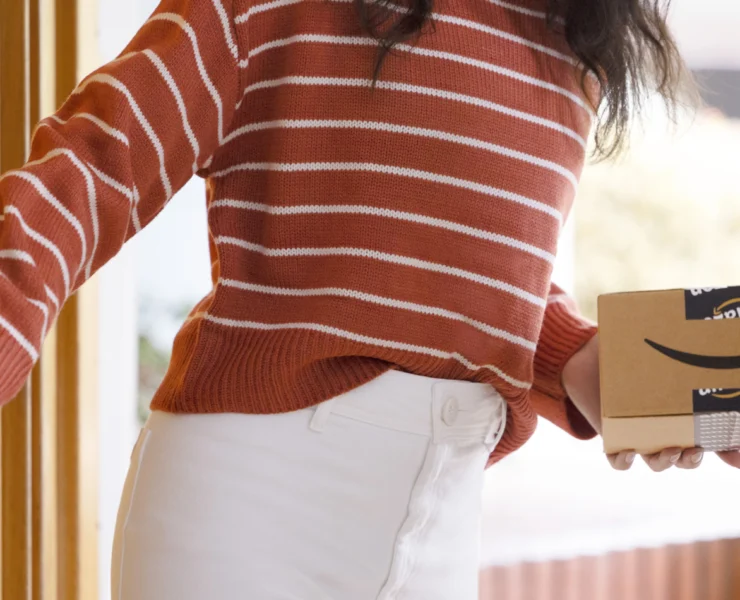 a woman holding an Amazon delivery package from the Amazon pharmacy