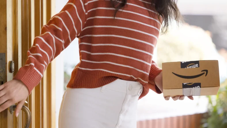 a woman holding an Amazon delivery package from the Amazon pharmacy