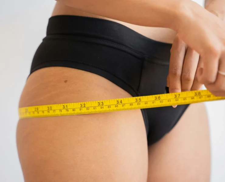 a woman measuring her body with measuring tape