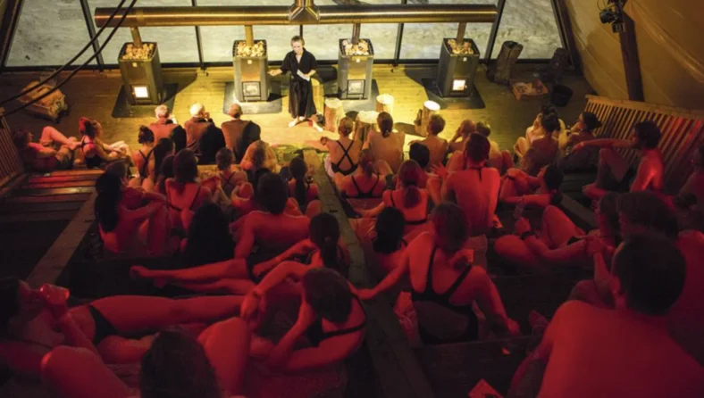 young people gather inside of a large sauna