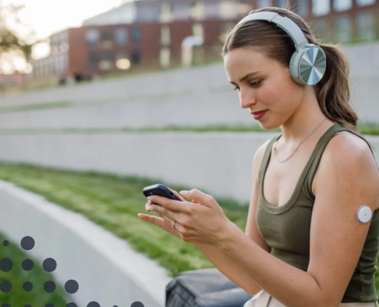 a woman checking the Cronometer app while wearing a CGM