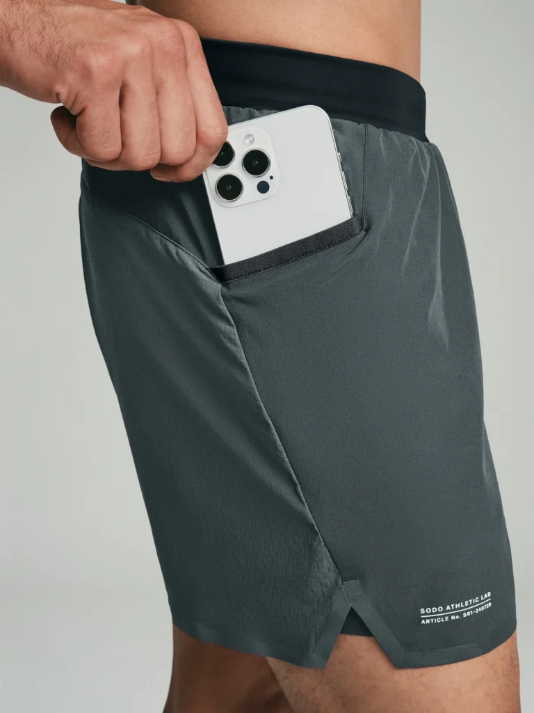 man places an iPhone into the pocket of his shorts