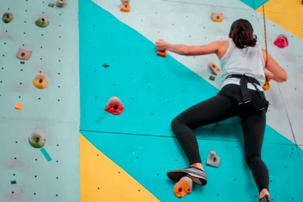 a woman bouldering at an indoor rock climbing gym