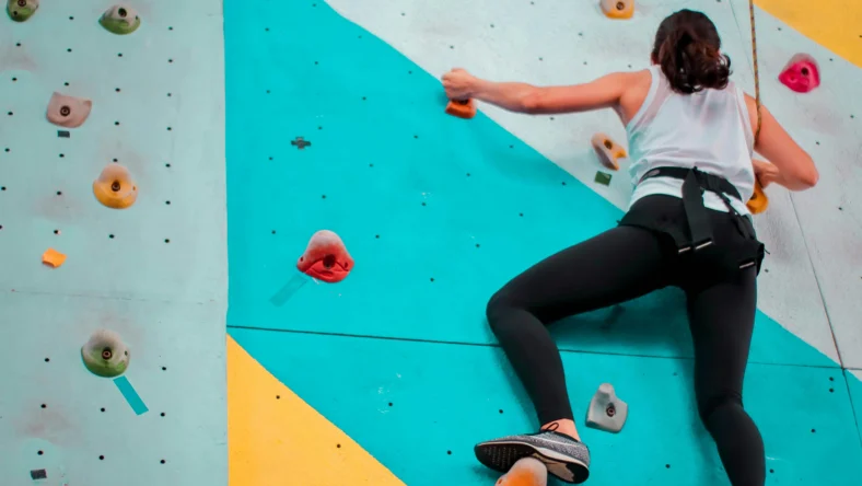 a woman bouldering at an indoor rock climbing gym