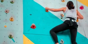 a woman bouldering at an indoor rock climbing gym