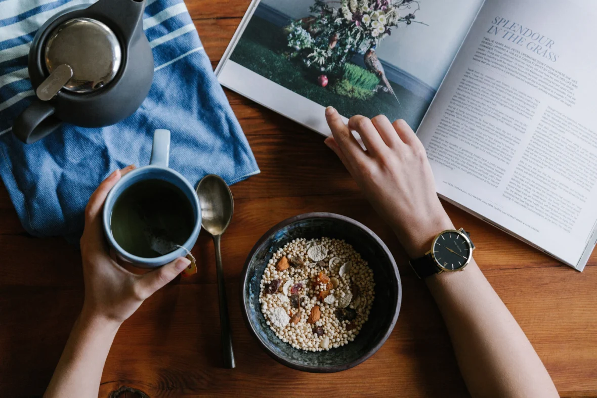 person holding blue mug and browsing a book