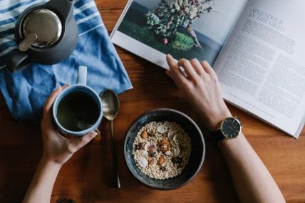 person holding blue mug and browsing a book