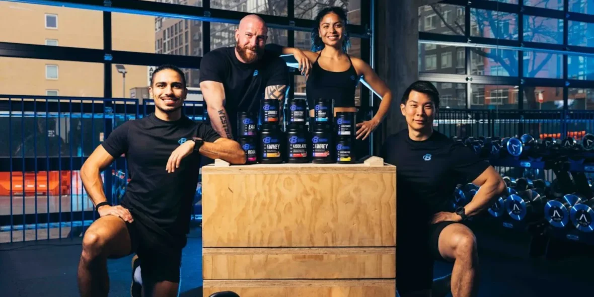 a group shot of people around Bodybuilding.com's supplements.