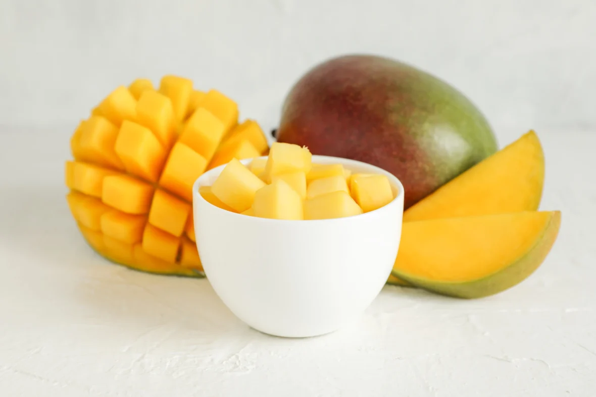 a cup of diced mango next to a whole mango