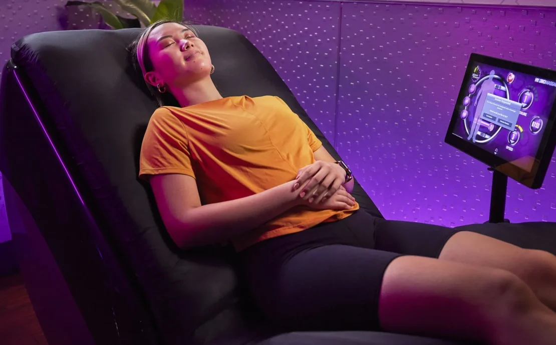 A woman is relaxing using the Planet Fitness HydroMassage lounger.