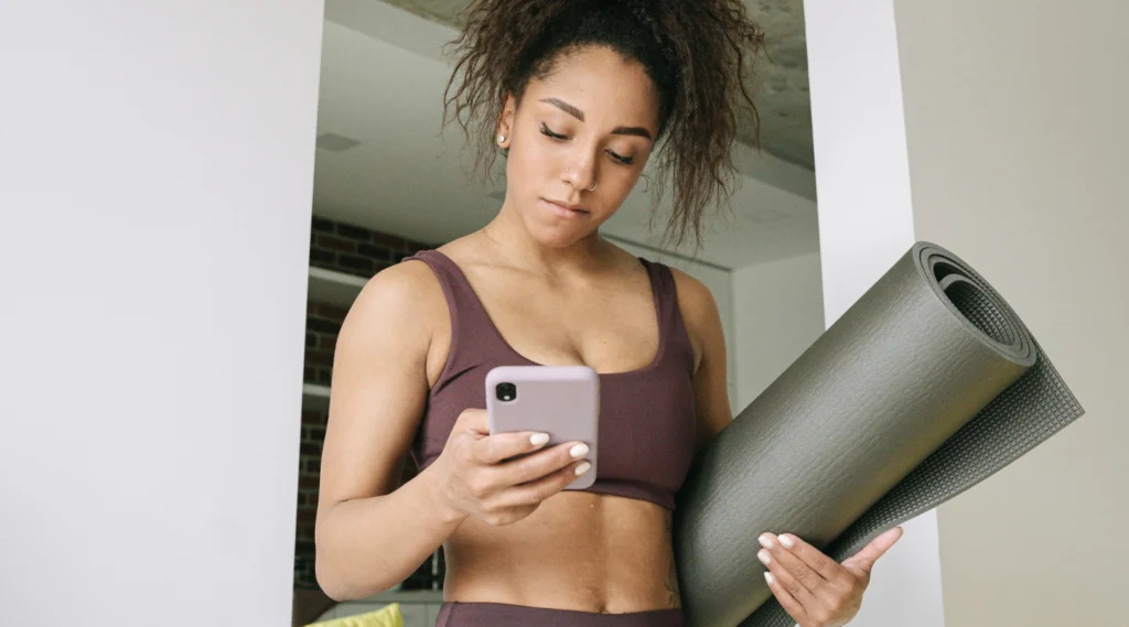 woman checks her phone after yoga class