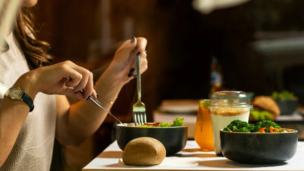 A woman eating a healthy bowl of food with a potato (?) next to her.