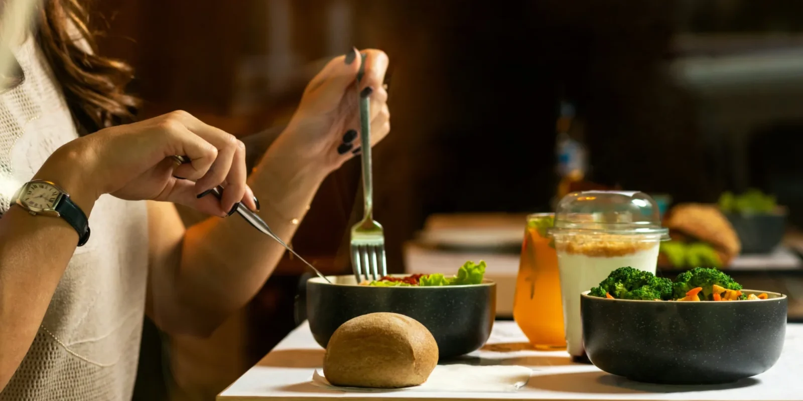 A woman eating a healthy bowl of food with a potato (?) next to her.