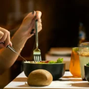 A woman eating a healthy bowl of food with a potato (?) next to her.